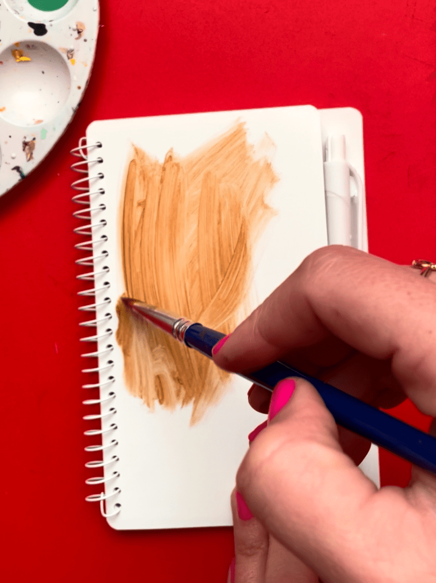 painting a blob of brown paint on a notebook